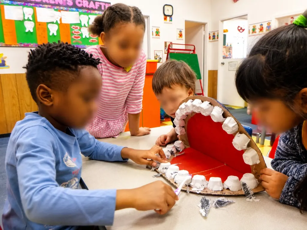 Children brushing a large model of teeth built from egg cartons during a health unit