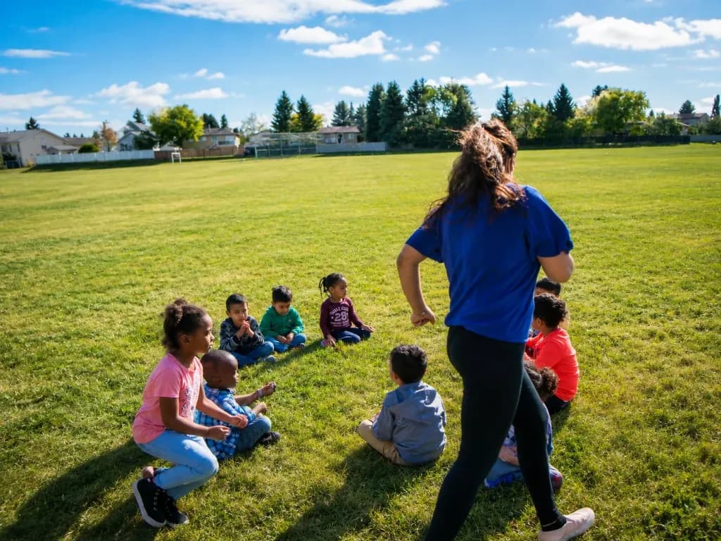 Children gathered on a grass field with an educator during a summer outing