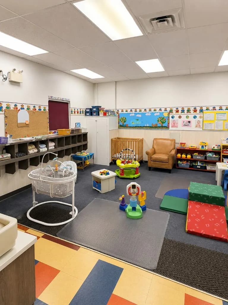 The Ideal Daycare infant room with a crib, soft play mats, and low shelving