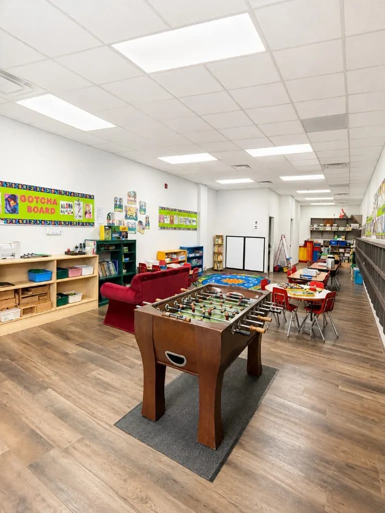 The out of school care room with a foosball table, reading area, and activity tables